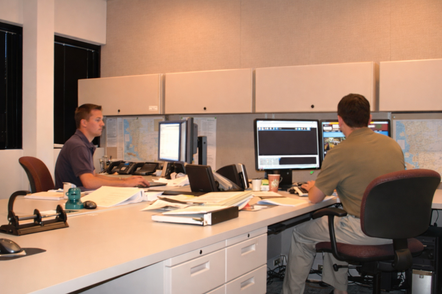 Two men sitting at a desk opposite of each other working