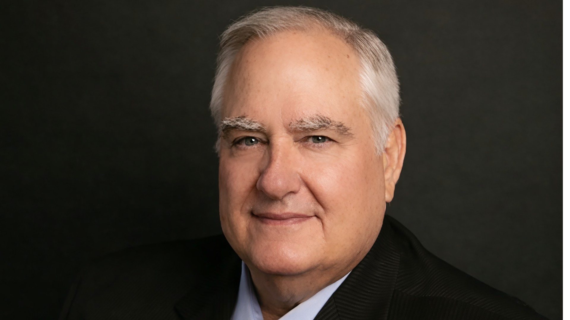 An older man with white hair smiling