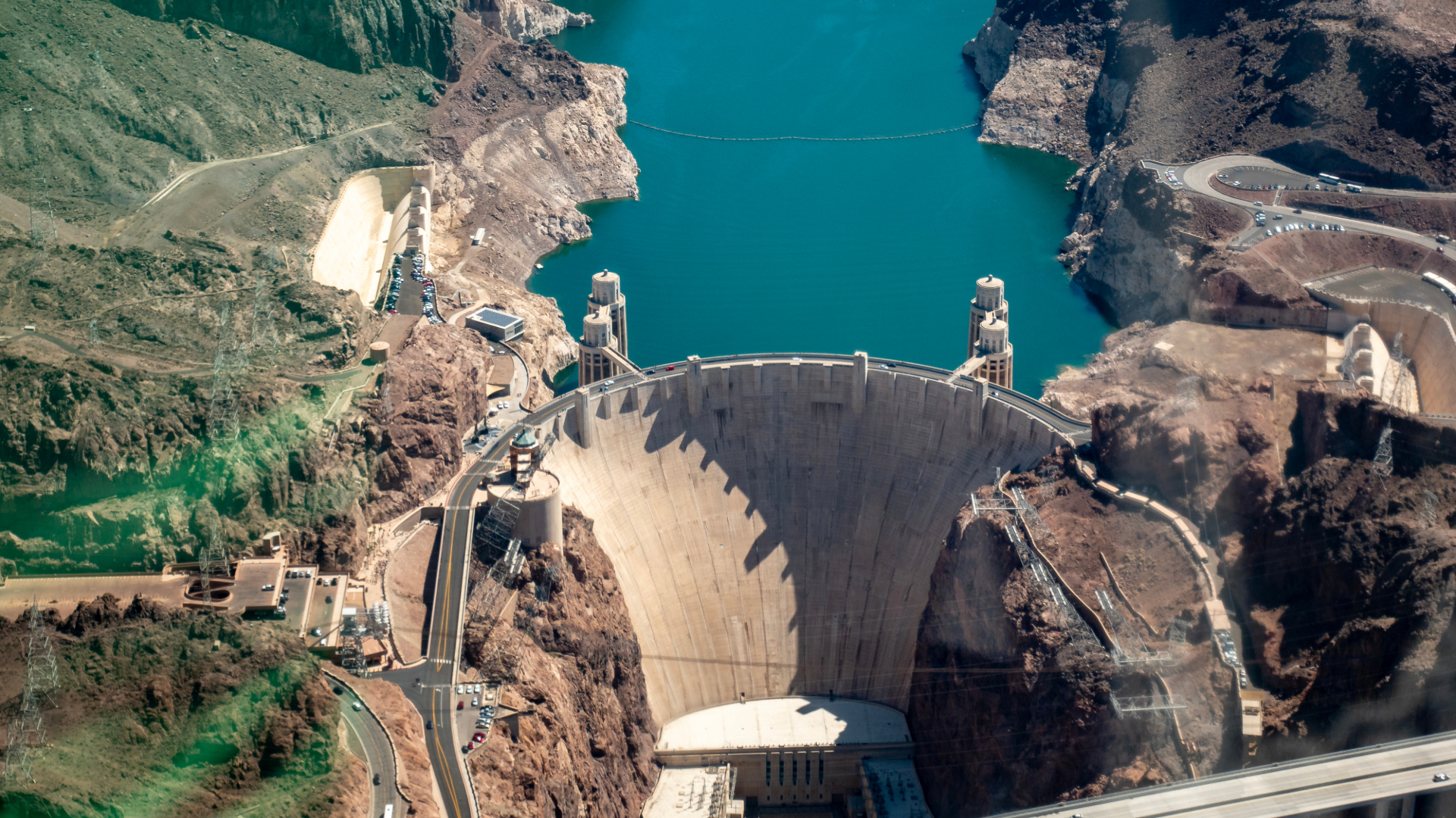 Cars driving on the Hoover Dam with the Lake Mead Reservoir in the back