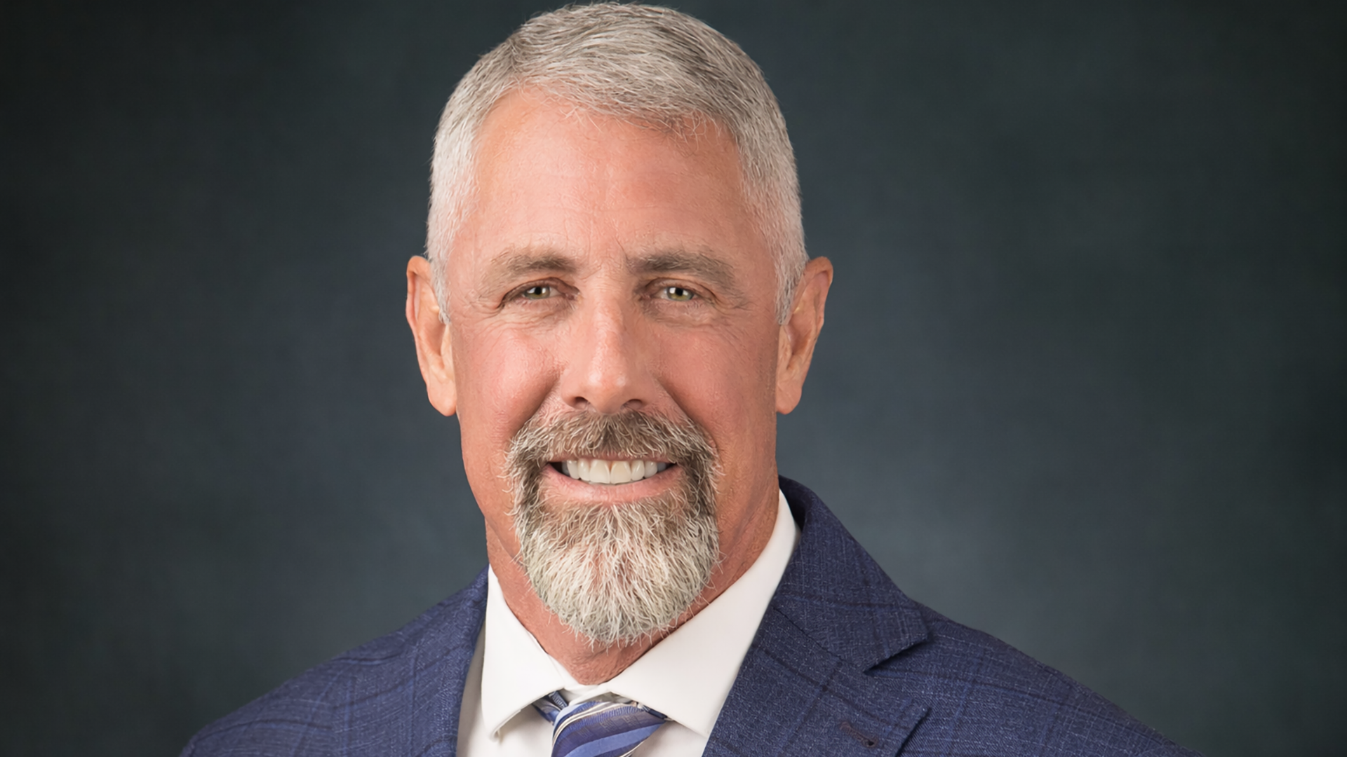 A man with white hair a white mustache smiling